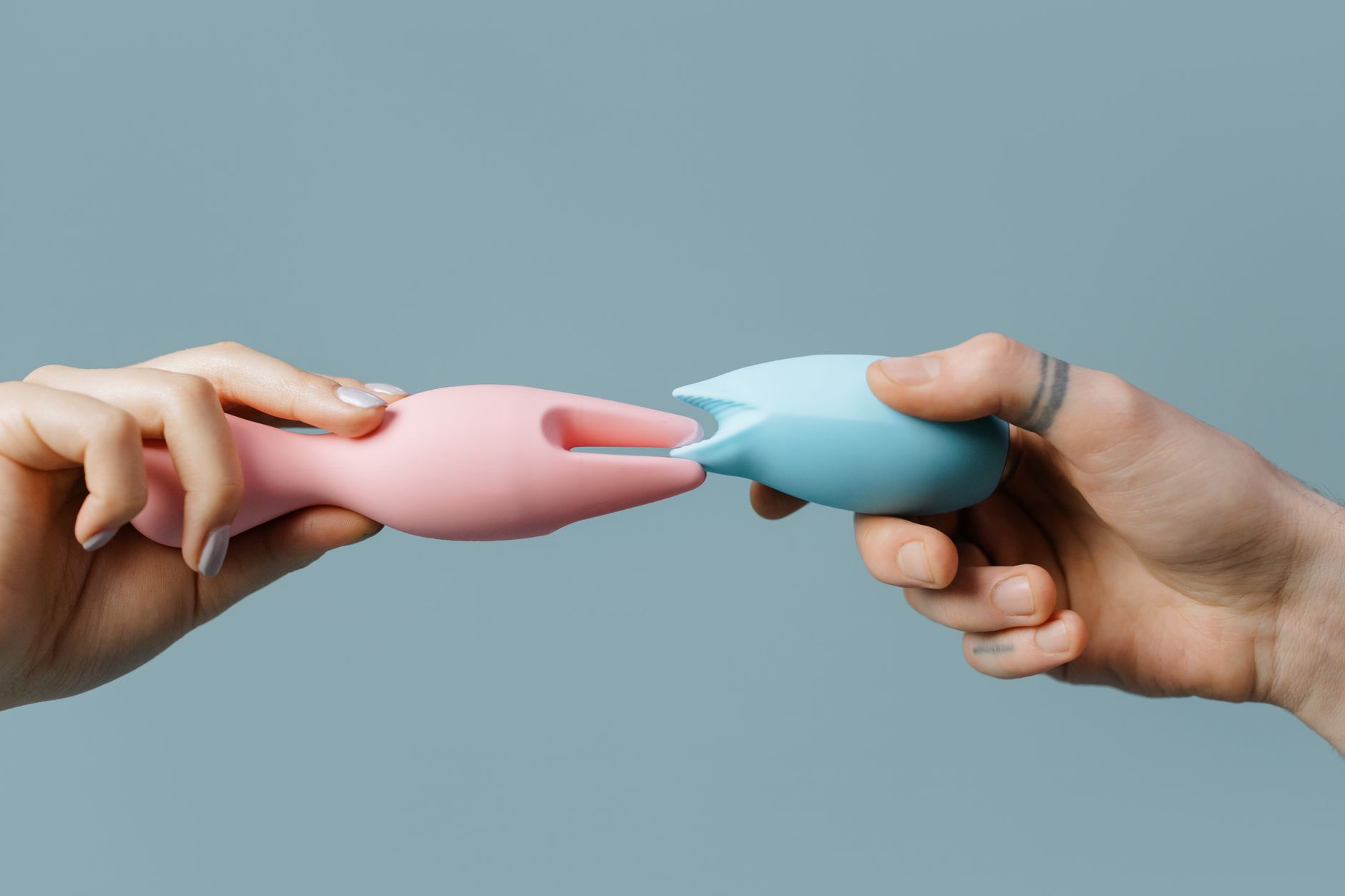 Hands holding silicone vibrators, representing partnered pleasure and intimacy